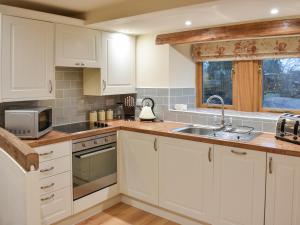 a kitchen with white cabinets and a sink at Pippa's Cottage - Uk42332 in Little Blencow +14 photos