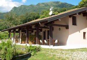 una casa blanca con sillas y montañas en el fondo en Agriturismo Da Gesi en Sale Marasino