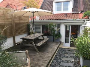 a wooden deck with a picnic table and an umbrella at Le sept in Ambleteuse