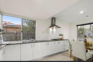 a kitchen with white cabinets and a table with chairs at Youth Castle in Brisbane