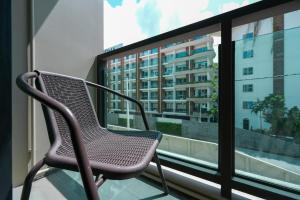 a chair sitting on a balcony in front of a window at New Condo near Bangtao Beach - Space Cherngtalay in Ban Thalat Choeng Thale