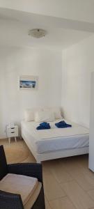 Un dormitorio con una cama blanca y una silla. en Gio st Gio apartment 2 Antiparos st Giorgio, en Agios Georgios
