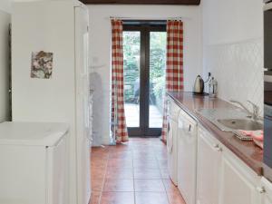 een keuken met witte kasten en een tegelvloer bij Dray Cottage in East Allington