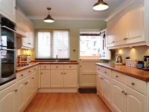 a kitchen with white cabinets and a window at Catbells Cottage Keswick in Keswick