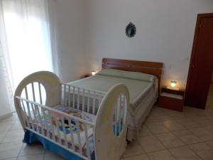 アルバ・アドリアティカにあるAppartamento Magnoliaのベッド付きの客室で、ベビーベッド1台を利用できます。