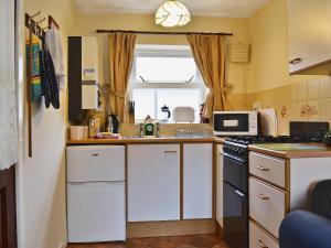 a kitchen with white cabinets and a microwave at Wrens Nest in Llanfair Caereinion