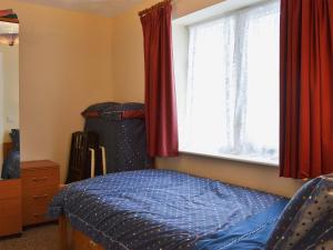 a bedroom with a bed and a window with red curtains at Wrens Nest in Llanfair Caereinion
