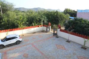 une voiture blanche garée sur un parking dans l'établissement Eagle farmstay, à Pushkar