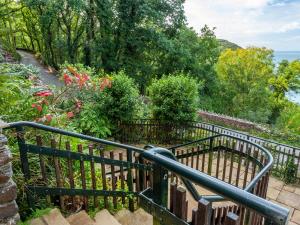 ein schwarzer Eisenzaun mit Blumen und Bäumen in der Unterkunft Haven Heights in Martinhoe