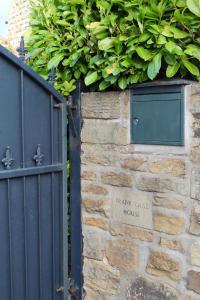 un mur en pierre avec un portail et un panneau sur celui-ci dans l'établissement Home in West Yorkshire with driveway and 3 double bedrooms - sleeps 6!, à Thornhill