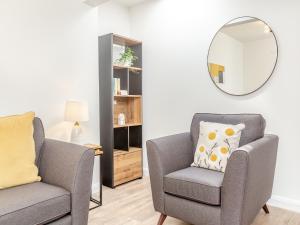 ein Wohnzimmer mit zwei Stühlen und einem Spiegel in der Unterkunft Dove Cottage in Inverness