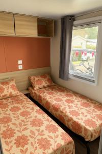 two beds in a small room with a window at Mobil-home 565 tout confort camping SIBLU 4 étoiles in Gastes +12 photos