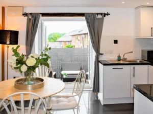eine Küche mit einem Tisch mit einer Vase mit Blumen darauf in der Unterkunft Oak Cottage in Abergavenny