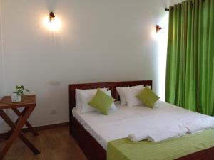 - une chambre avec un lit et un rideau vert dans l'établissement Paddi Breeze Cottage - Yala Safari, à Lukasgoda