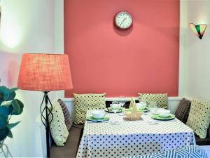 ein Esstisch mit einer Uhr an einer roten Wand in der Unterkunft Quill Corner in Alnwick