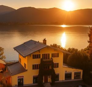 a house with solar panels on its roof next to a lake at Villa Tegernsee - Exclusive Lakefront Villa with private Zirben Sauna, 4 Rooms for Family & Friends in Tegernsee