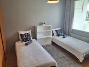 a room with two beds and a shelf and a window at LibO-apartment, Inkilä 23 X in Kuopio