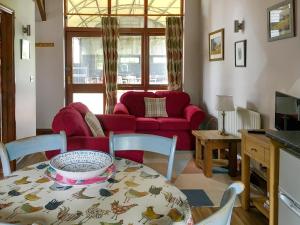 a living room with a table and a red couch at Heron in Welney