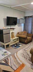 a living room with a couch and a flat screen tv at Gloria's mini hideaway in Christ Church