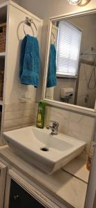 a bathroom with a sink and a mirror and blue towels at Gloria's mini hideaway in Christ Church