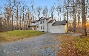 uma casa branca com garagem em cima de uma entrada para carros em Lake Area 6BR Pet friendly home in Poconos - Your Pocono Retreat em Thornhurst