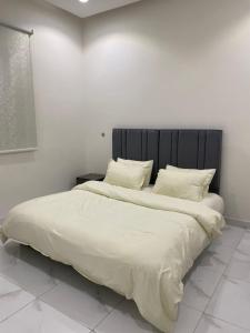 a bedroom with a large bed with white sheets and pillows at شقق المصيف الفندقيه in Hafr Al Baten