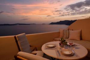 ein Tisch und Stühle auf einem Boot mit einem Tisch und einem Tisch in der Unterkunft THE A COLLECTION by K&K in Oia