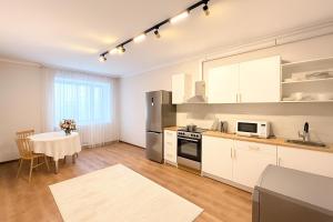 une cuisine avec des placards blancs et une table avec une salle à manger dans l'établissement Keruen shopping mall, Abu Dhabi Plaza shopping mall, Baiterek, à Astana