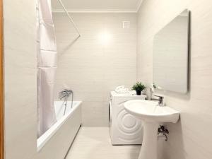 une salle de bain blanche avec un lavabo et un miroir dans l'établissement Keruen shopping mall, Abu Dhabi Plaza shopping mall, Baiterek, à Astana