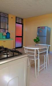 a kitchen with a stove and a table and a refrigerator at Departamento amoblado en primer piso 200 MTS a tu disposición con todos los servicios in Tacna