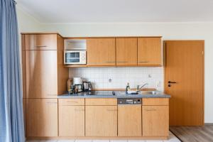 a kitchen with wooden cabinets and a sink and a microwave at Inselglück App 1 in Norderney
