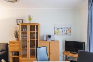 a living room with a tv and a desk with a computer at Inselglück App 1 in Norderney
