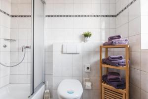 a bathroom with a toilet and a shower with purple towels at Inselglück App 1 in Norderney +8 photos