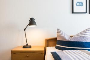 a lamp on a night stand next to a bed at Inselglück App 2 in Norderney +7 photos