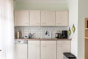 a kitchen with white cabinets and a sink at Mayglück App 1 in Norderney