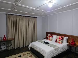 a bedroom with a bed with white sheets and red pillows at Nandoni Maritime Home in Thohoyandou