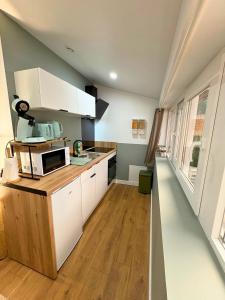 Una cocina con gabinetes blancos y un microondas. en La Bulle Secrète, en Villeneuve-sur-Lot