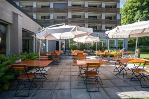 Un patio al aire libre con mesas, sillas y sombrillas. en Studio Top im des Alpes, en Flims