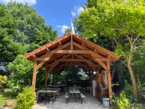 a wooden pavilion with tables and tables in a park at Gîte Camping les Arbois in Montjay
