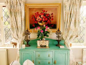 ein Gemälde einer Blumenvase auf einem Schrank in der Unterkunft Kipling Cottage in Burwash