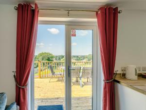 a door leading to a patio with red curtains at Hill Crest Lodge 1 in Hemswell