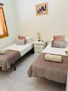 a bedroom with two beds and a dresser with a lamp at Villa Limon Playa Flamenca in Alicante +36 photos