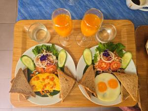 two plates of food on a table with glasses of orange juice at Beach Home Lanta in Ko Lanta
