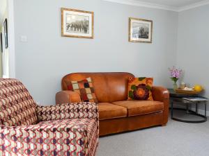 ein Wohnzimmer mit einer Couch und einem Sessel in der Unterkunft Three Creeks Cottage in Portknockie