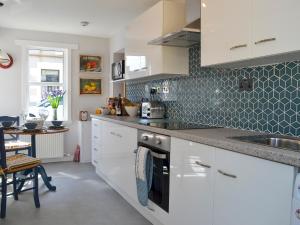 eine Küche mit weißen Schränken und einer Spüle in der Unterkunft Three Creeks Cottage in Portknockie