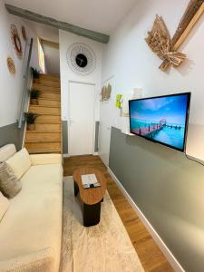 Una sala de estar con un sofá y un televisor en una pared. en La Bulle Secrète, en Villeneuve-sur-Lot