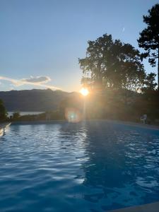 a swimming pool with the sunset in the background at Appartamento in residence con piscina in Luino