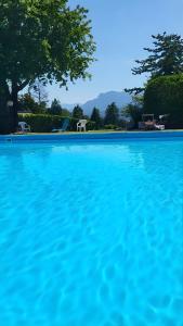 a blue swimming pool with chairs and trees in the background at Appartamento in residence con piscina in Luino
