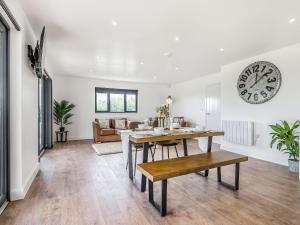 a living room with a table and a clock on the wall at Oak Tree Lodge - Uk38383 in Lyonshall +19 photos