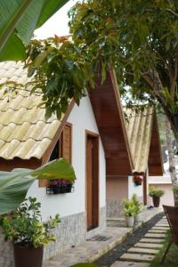 a white house with wooden doors and potted plants at Chalé Sognare Uno in Santa Teresa